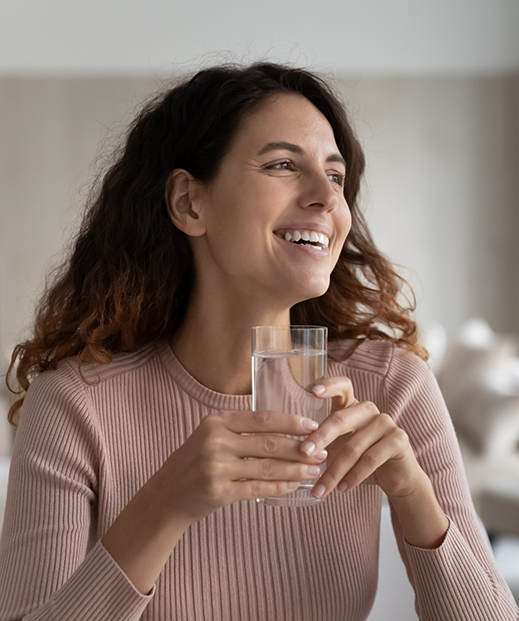 Smiling woman holding a glass of water in a psychiatry office in Austin