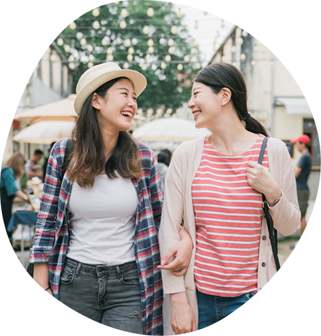 Two women smiling at each other while walking down a street