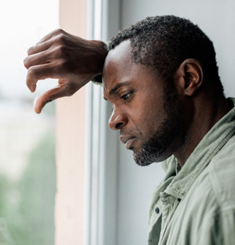 Sad man leaning against a window