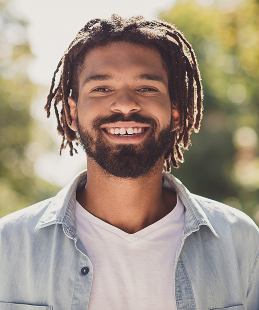 Man in a denim shirt smiling in the sun