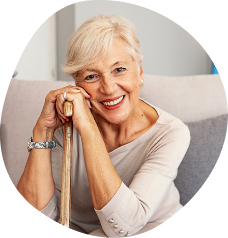Smiling woman sitting on a couch and leaning against her cane