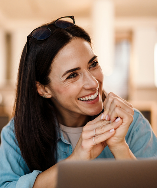 Woman smiling while sitting at a table with a laptop
