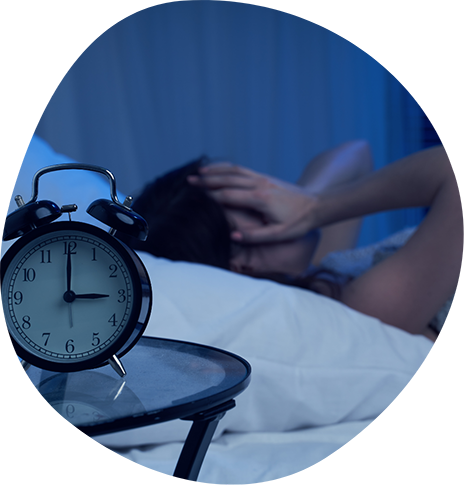 Person laying awake in bed while a bedside clock reads three AM
