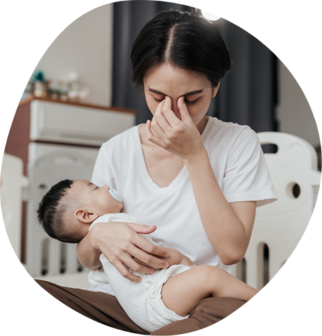 Woman pinching the bridge of her nose while holding her baby