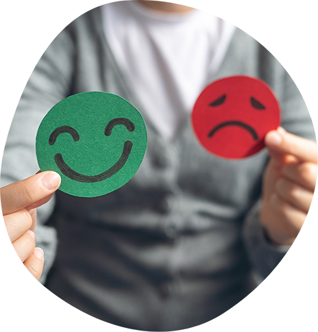 Person holding a green happy face circle and a red sad face circle